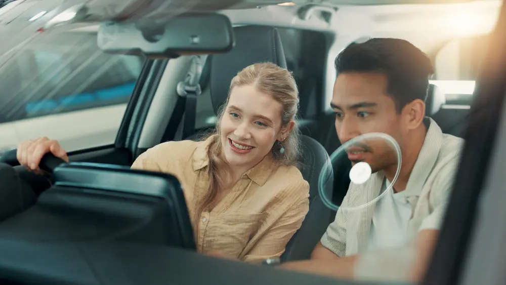 O que verificar durante o test drive? Mulher sorrindo ao volante durante test drive de carro na concessionária
