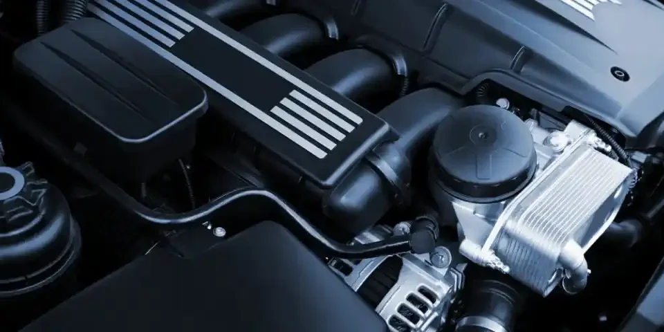 Detalhe de um motor aspirado com componentes visíveis sob o capô de um carro