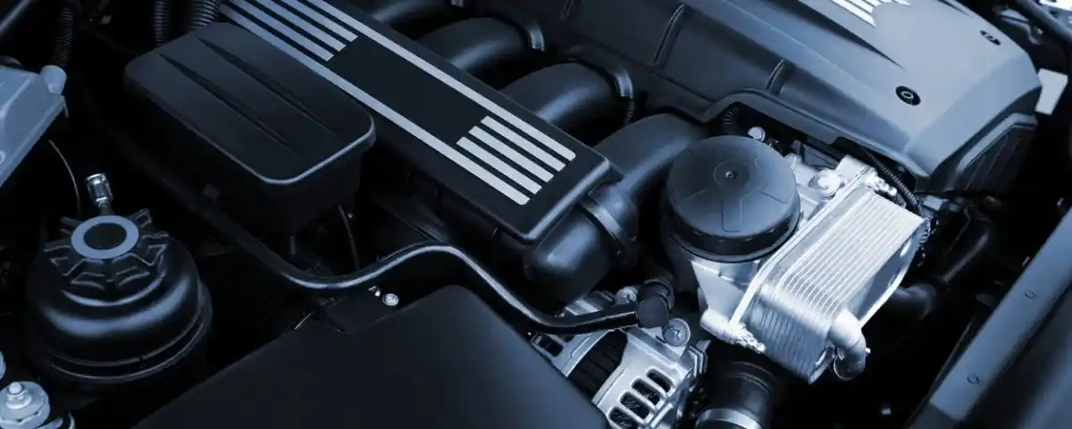 Detalhe de um motor aspirado com componentes visíveis sob o capô de um carro