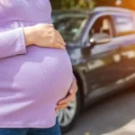 Gestante ao lado de um carro, ilustrando a dúvida "grávida pode dirigir até quando"