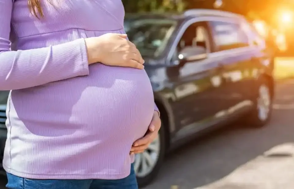 Gestante ao lado de um carro, ilustrando a dúvida "grávida pode dirigir até quando"