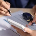 Pessoa assinando contrato de leasing de carros com chave e miniatura de veículo sobre a mesa