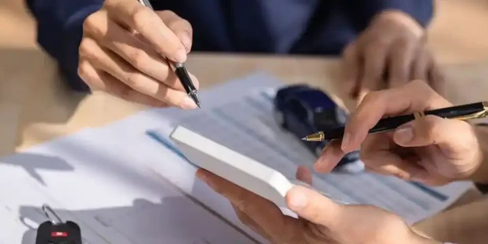 Pessoa assinando contrato de leasing de carros com chave e miniatura de veículo sobre a mesa