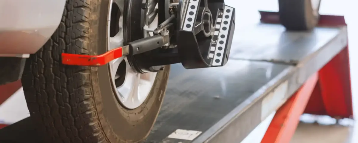 Carro em máquina de alinhamento e balanceamento de rodas em oficina automotiva.