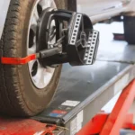 Carro em máquina de alinhamento e balanceamento de rodas em oficina automotiva.