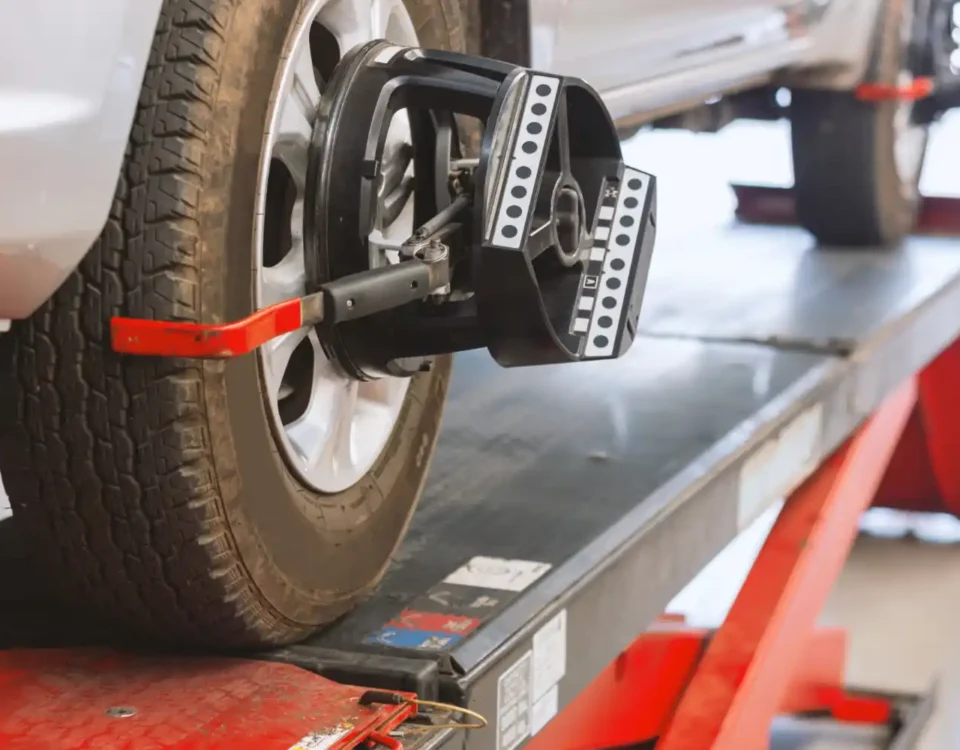 Carro em máquina de alinhamento e balanceamento de rodas em oficina automotiva.
