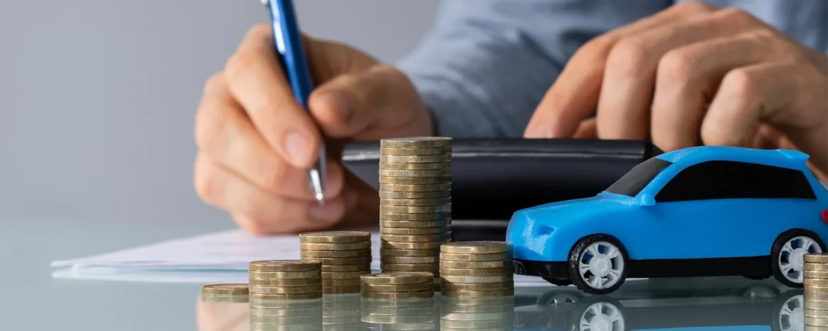 Pilha de moedas ao lado de um carro azul simbolizando refinanciamento de veículo e planejamento financeiro automotivo