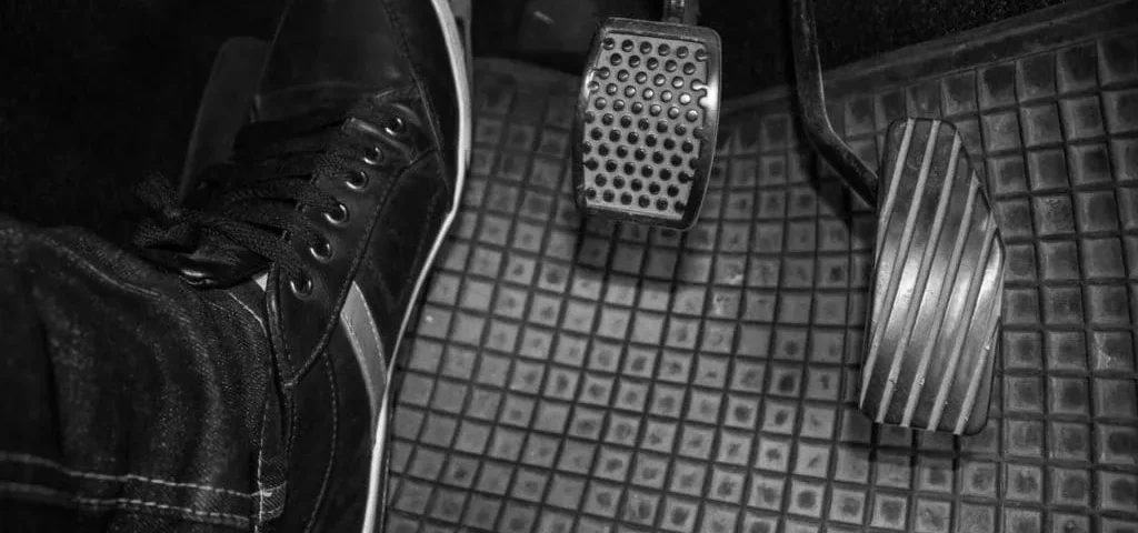 Carro com embreagem dura, mostrando pedal de embreagem pesado e dificuldade no acionamento ao dirigir.